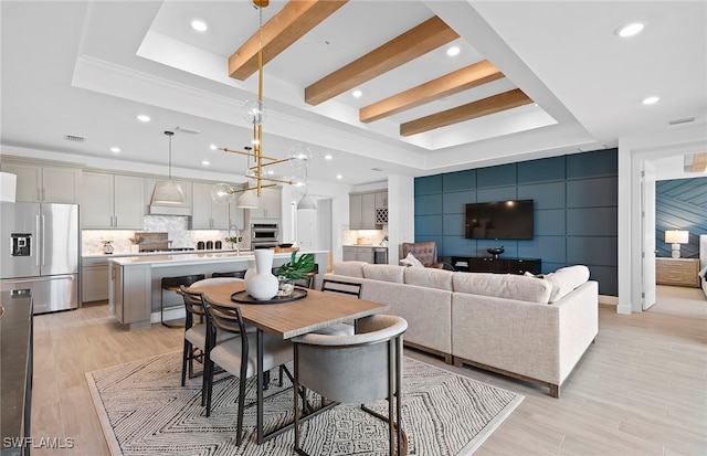 living room with light hardwood / wood-style floors, an inviting chandelier, crown molding, a tray ceiling, and beam ceiling