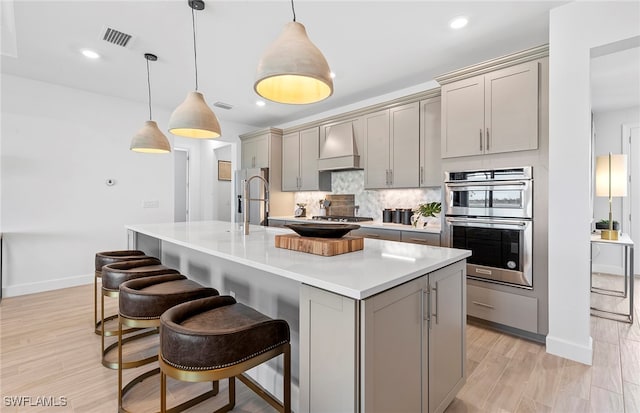 kitchen featuring gray cabinetry, hanging light fixtures, premium range hood, and stainless steel appliances