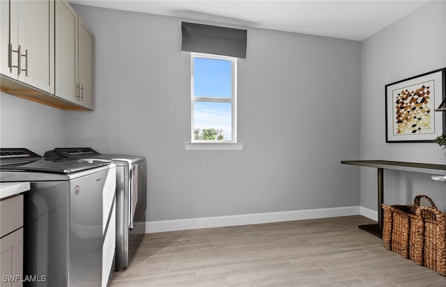 laundry area with cabinets, washing machine and clothes dryer, and light hardwood / wood-style flooring