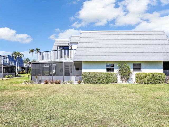 rear view of property with a sunroom, a balcony, and a yard