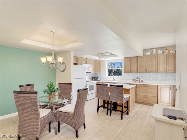 tiled dining space with a tray ceiling and a chandelier