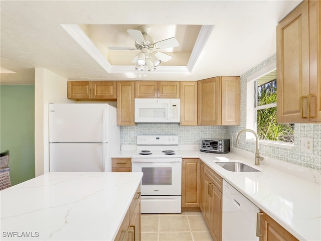 kitchen with light stone counters, white appliances, sink, and a tray ceiling