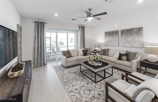 living room with light hardwood / wood-style flooring, wooden walls, and ceiling fan