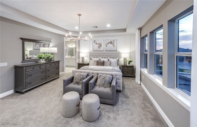 carpeted bedroom featuring a tray ceiling, a notable chandelier, and ensuite bathroom