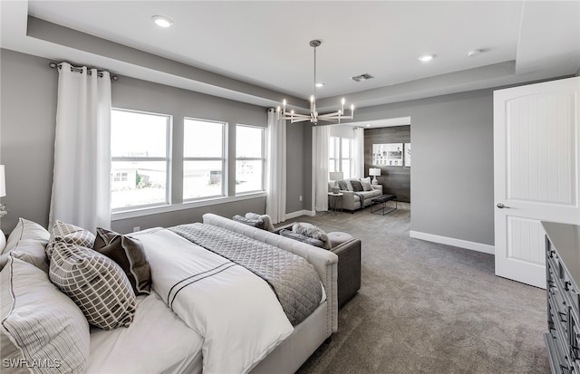 carpeted bedroom featuring multiple windows, a raised ceiling, and a notable chandelier