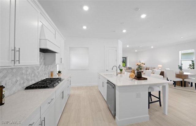 42202 Lake Timber Dr, Punta Gorda, FL 33982 - kitchen with stainless steel appliances, backsplash, white cabinets, a kitchen breakfast bar, and light wood finished floors