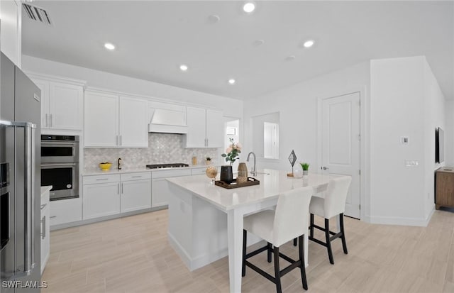42202 Lake Timber Dr, Punta Gorda, FL 33982 - kitchen with stainless steel appliances, white cabinets, light countertops, an island with sink, and recessed lighting