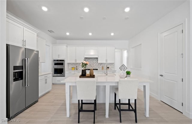 42202 Lake Timber Dr, Punta Gorda, FL 33982 - kitchen with appliances with stainless steel finishes, light countertops, white cabinetry, decorative backsplash, and an island with sink