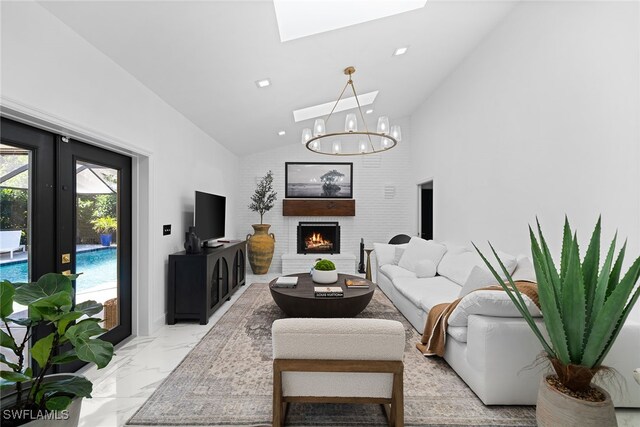 living room featuring a chandelier, a brick fireplace, and vaulted ceiling