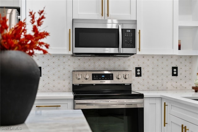 kitchen featuring tasteful backsplash, white cabinetry, and appliances with stainless steel finishes