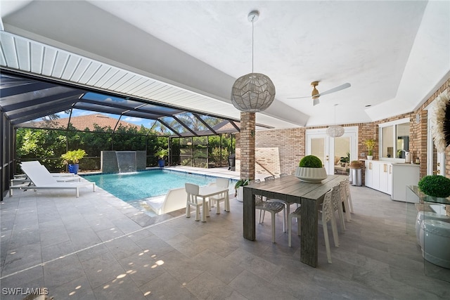 view of swimming pool featuring pool water feature, a lanai, a bar, a patio area, and exterior kitchen