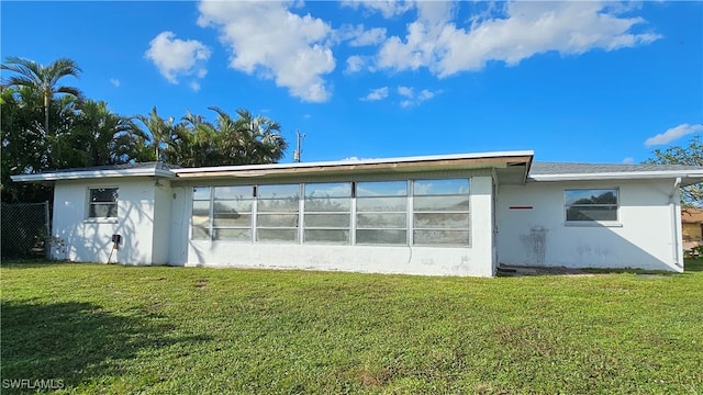 back of property with a sunroom and a yard