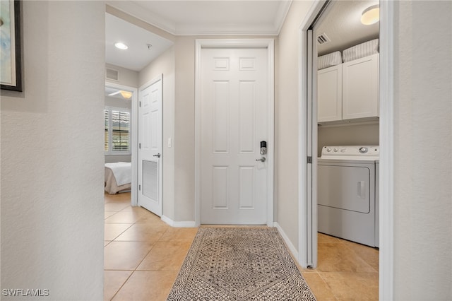 interior space featuring washer / clothes dryer, cabinets, light tile patterned floors, and crown molding