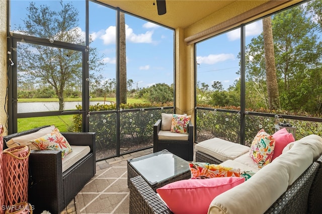 sunroom with ceiling fan and a water view