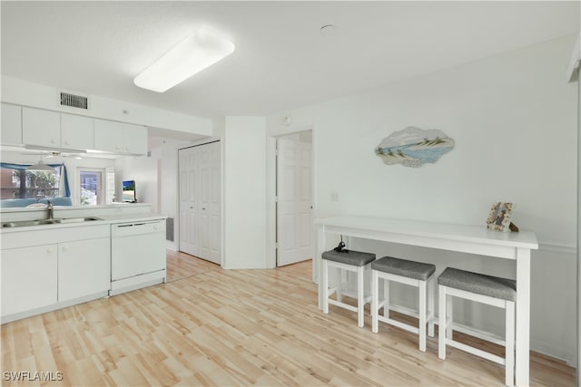 kitchen featuring light hardwood / wood-style floors, white cabinetry, sink, a breakfast bar area, and dishwasher