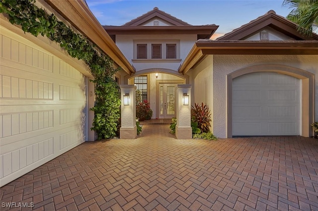 exterior entry at dusk featuring a garage