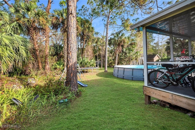 view of yard featuring a sunroom and a trampoline