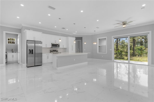 kitchen featuring appliances with stainless steel finishes, pendant lighting, a center island with sink, washing machine and clothes dryer, and white cabinets