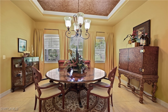 tiled dining room featuring a raised ceiling, ornamental molding, and an inviting chandelier