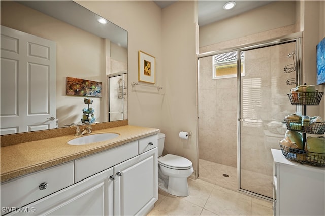 bathroom with tile patterned flooring, vanity, a shower with shower door, and toilet