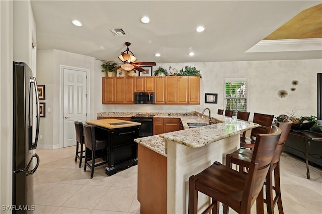 kitchen featuring a kitchen bar, appliances with stainless steel finishes, light stone countertops, and sink