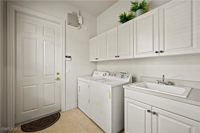 clothes washing area with washing machine and clothes dryer, sink, light tile patterned floors, and cabinets