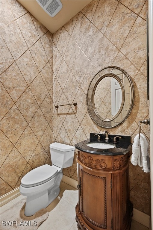 bathroom featuring vanity, toilet, and tile walls