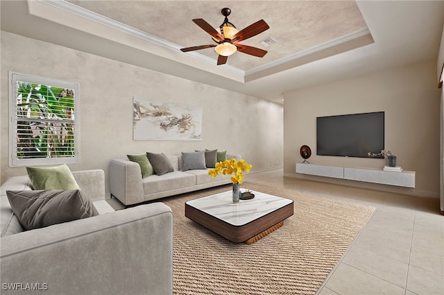 tiled living room featuring a tray ceiling, ceiling fan, and ornamental molding