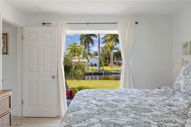 bedroom featuring a water view and light hardwood / wood-style flooring