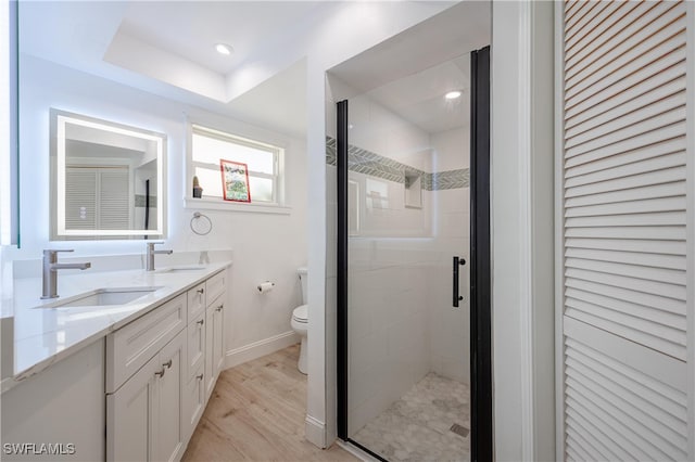 bathroom with hardwood / wood-style floors, vanity, toilet, and walk in shower