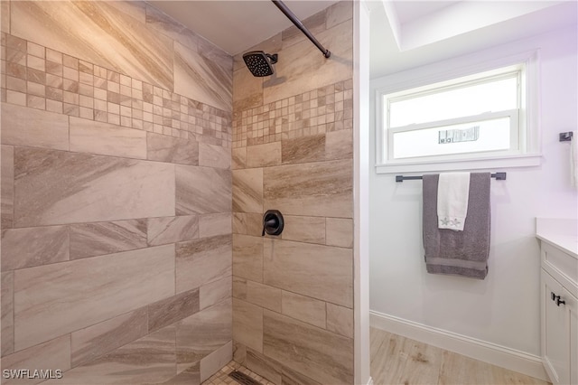 bathroom featuring vanity, wood-type flooring, and tiled shower