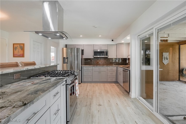 kitchen featuring light stone countertops, sink, stainless steel appliances, light hardwood / wood-style flooring, and range hood