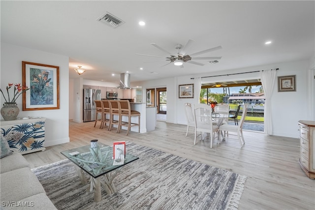 living room with light hardwood / wood-style flooring, ceiling fan, and a healthy amount of sunlight