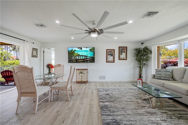 living room featuring ceiling fan, a healthy amount of sunlight, a textured ceiling, and light hardwood / wood-style flooring