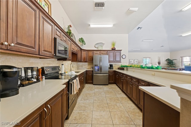 kitchen featuring stainless steel appliances, light tile patterned flooring, sink, kitchen peninsula, and tasteful backsplash