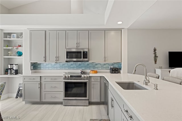 kitchen featuring gray cabinetry, appliances with stainless steel finishes, sink, and tasteful backsplash