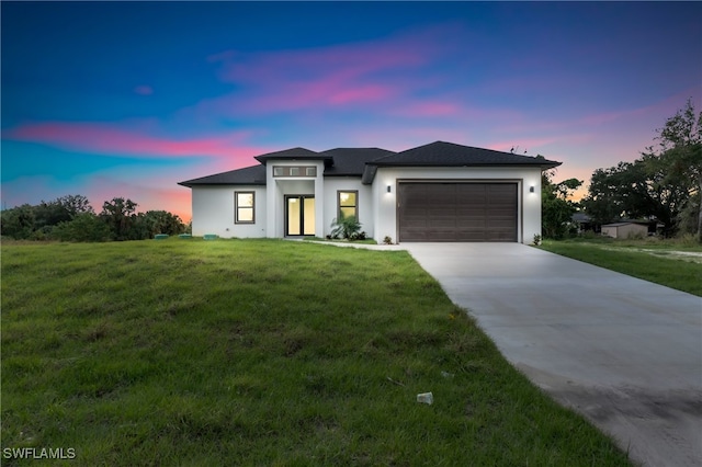 view of front of home with a garage and a lawn