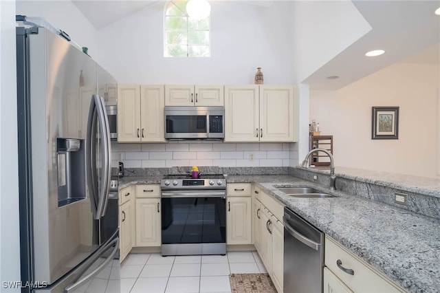 kitchen with stainless steel appliances, backsplash, light stone countertops, sink, and cream cabinetry