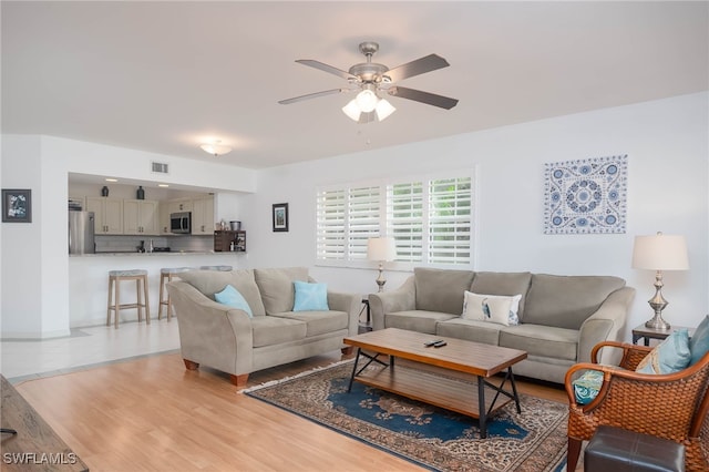 living room with light hardwood / wood-style flooring and ceiling fan