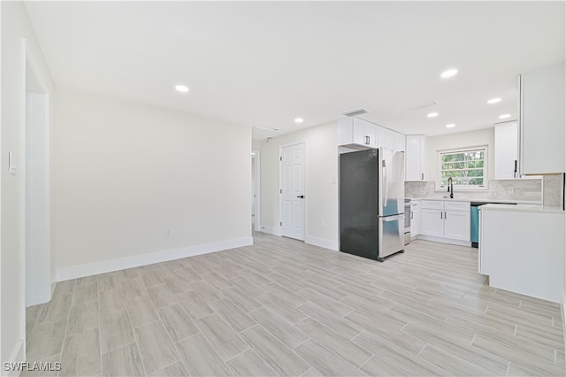 kitchen with light hardwood / wood-style flooring, decorative backsplash, stainless steel fridge, and white cabinets