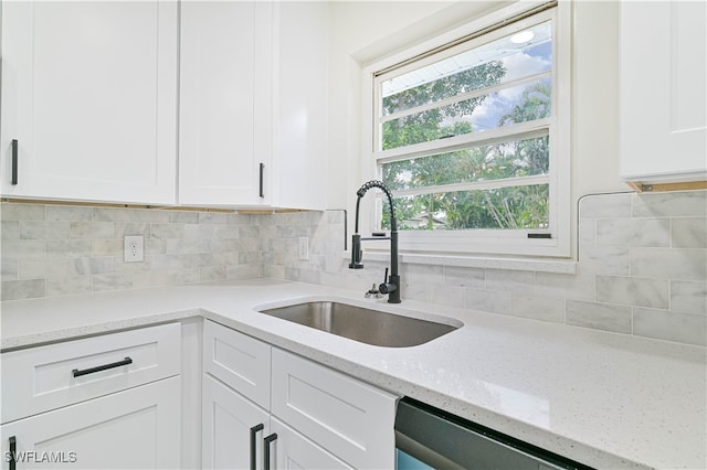 kitchen featuring dishwasher, sink, tasteful backsplash, light stone countertops, and white cabinetry