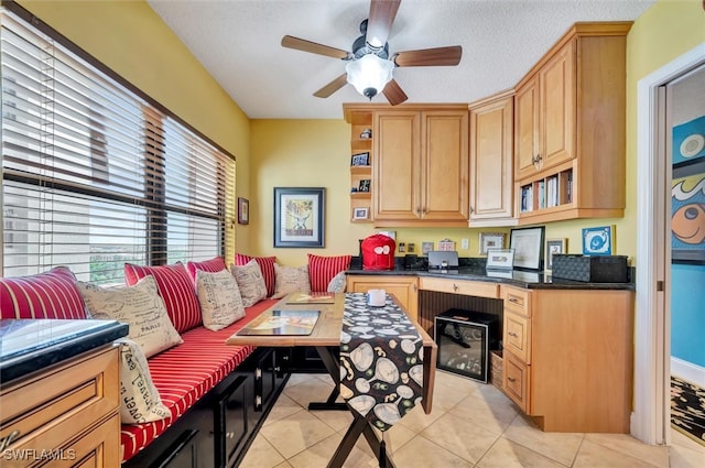 tiled home office featuring a textured ceiling, ceiling fan, and built in desk