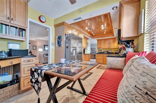 kitchen featuring light tile patterned flooring, stainless steel refrigerator with ice dispenser, light brown cabinetry, and a raised ceiling