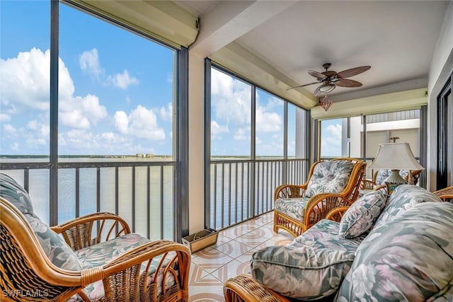 sunroom with a healthy amount of sunlight, a water view, and ceiling fan