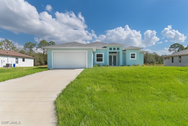 view of front of home with a garage, cooling unit, and a front yard