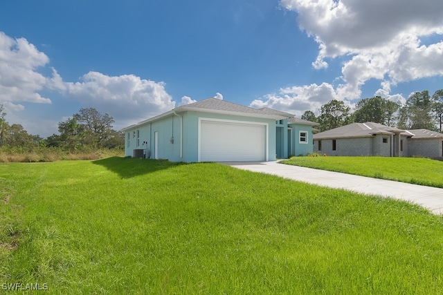 view of front of home with a front yard, central AC, and a garage