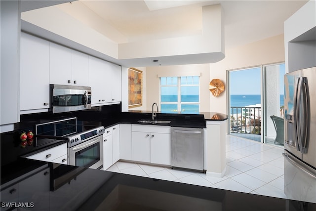 kitchen with white cabinets, a water view, sink, light tile patterned floors, and stainless steel appliances