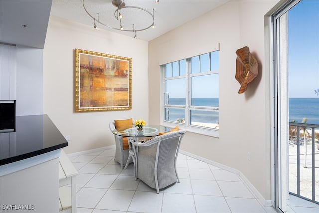 dining space with light tile patterned floors and a water view