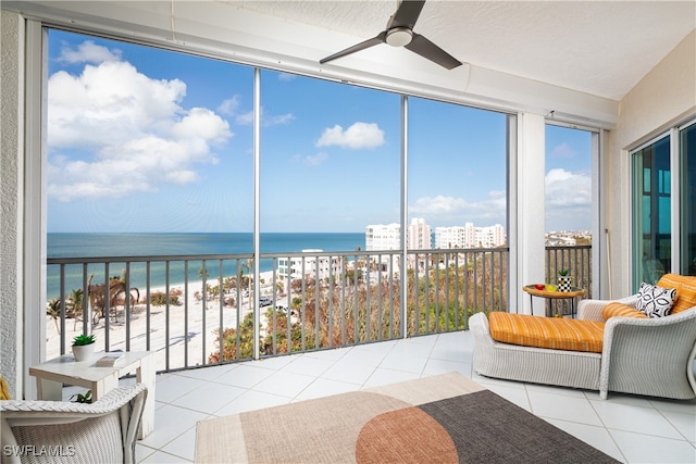 sunroom / solarium with ceiling fan, a water view, and a beach view