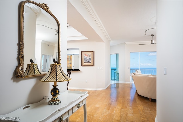 hallway featuring a water view, ornamental molding, and light wood-type flooring